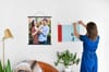 A woman hangs two Fine Art Photo Prints with black poster rails and silver skeleton clips.
