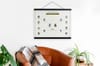 A Family Tree Poster hangs from black magnetic poster rails over a comfortable leather chair.