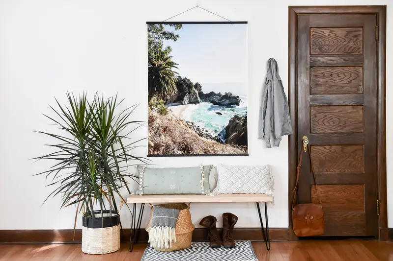An Engineer Print of a coastal photo hangs from black Wood Poster Rails above an entryway bench