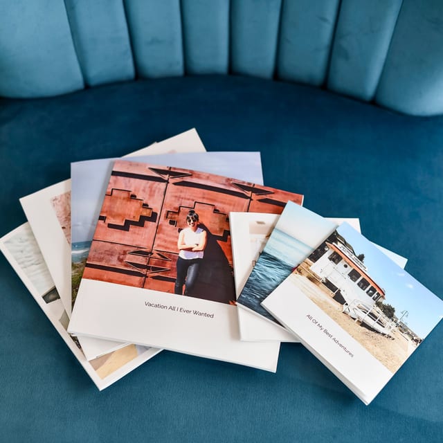 Several Softcover Photo Books scattered on a blue velvet chair, with travel photo covers and captions. Several Softcover Photo Books scattered on a blue velvet chair, with travel photo covers and captions.