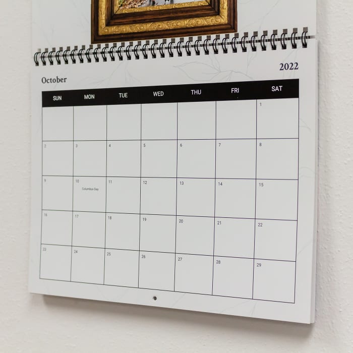 A close-up of a custom Family Photo Wall Calendar shows the crisp high quality printing and black metal wire binding.