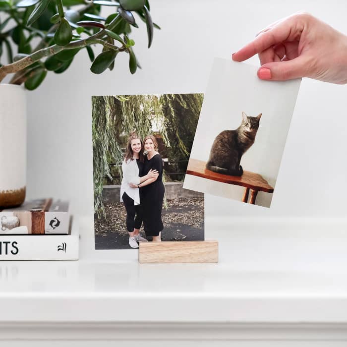 A Classic Print of two women is displayed using a Wood Block. A hand reaches in holding a photo of a cat.