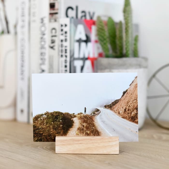 A Classic Print of a person standing on a foggy mountainside is displayed on a desk using a wood block.