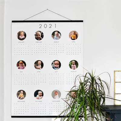 An Engineer Print Calendar hangs from black Wood Poster Rails. There is a round photo above each month of the year. An Engineer Print Calendar hangs from black Wood Poster Rails. There is a round photo above each month of the year.