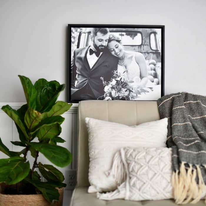 A Canvas Print of a wedding photo in a Black Frame is placed on a ledge behind a couch.