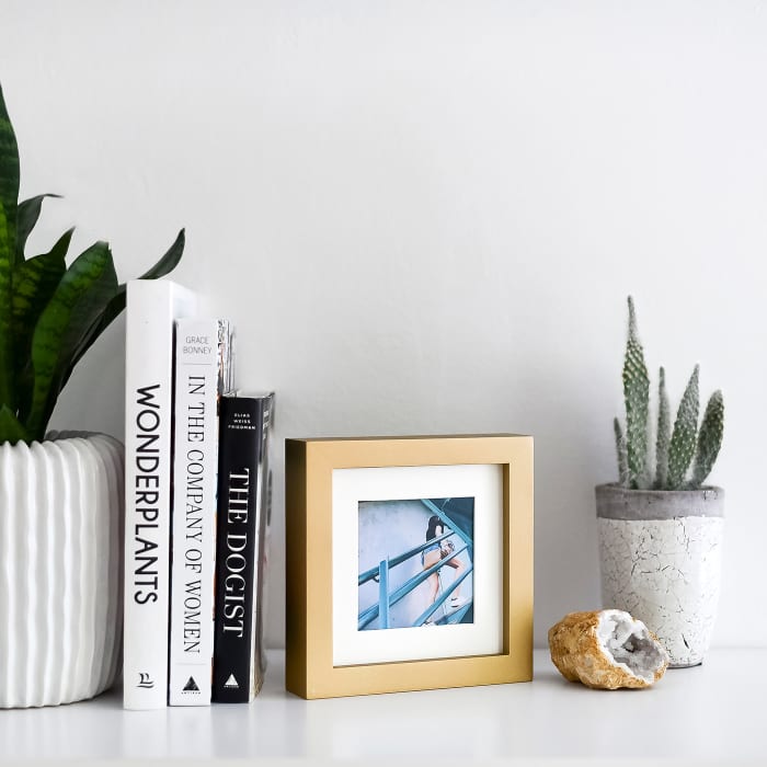 A Gold Square Frame decorates a bookshelf.