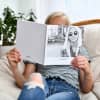 A girl looks at a Hardcover Photo Book titled, Los Angeles, California, with a Black and White portrait on the cover.