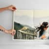 Hands hold a Newsprint of a traveler on a bridge. The Newsprint has crisp creases from being folded in fourths.