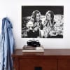 A black and white Newsprint of a photo of two children laughing hangs from Good Hangups above a dresser.