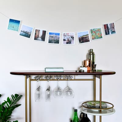 A 58 inch Horizontal Photo Rope full of prints is draped over a a bar cart to display Square Prints. A 58 inch Horizontal Photo Rope full of prints is draped over a a bar cart to display Square Prints.