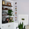 A column of photo prints showing fun family photos on a Vertical Photo Rope hang next to a bookshelf.