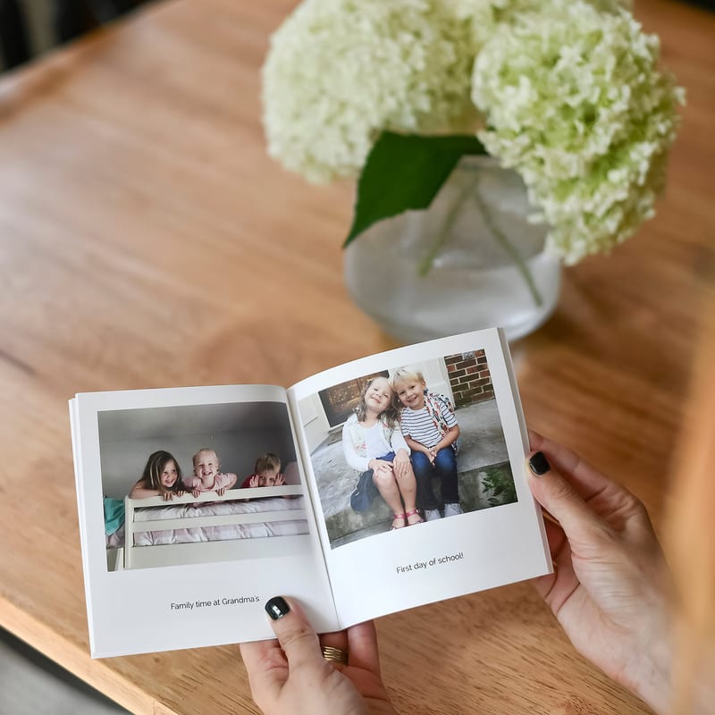 Hands holding a small softcover photo book.