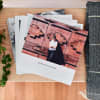 A stack of 8 inch Softcover Photo Books is fanned out on a table. The top book cover shows a fun vacation.