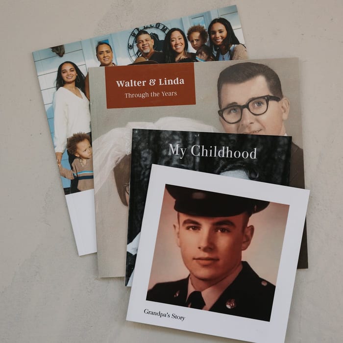 A fanned stack of four MyCanvas Softcover Photo Books, with covers titled Walter & Linda Through the Years, My Childhood, and Grandpa's Story.