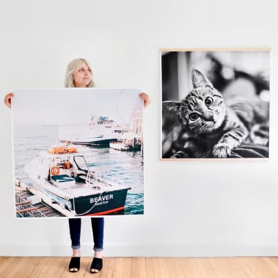 A person stands holding a Square Engineer Print. Another black and white print hangs on the wall behind them.