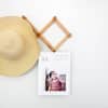 A 12 inch tall Keepsake Wall Calendar showing a cute photo of a girl hangs from a coat hook alongside a straw hat.