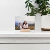 A photo of two friends is displayed in an oak wood block on a mantle.